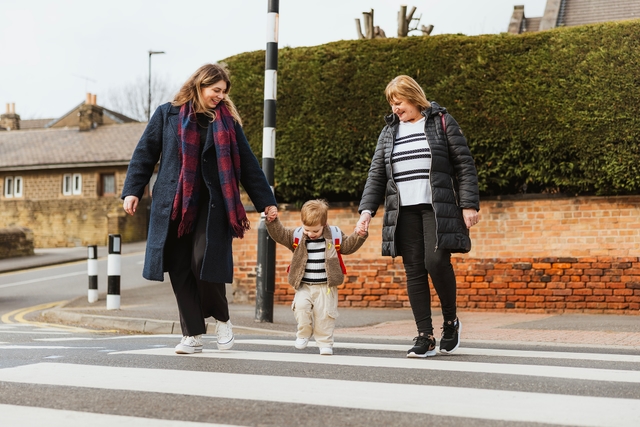 Little boy on zebra crossing holding hands with mum and grandma