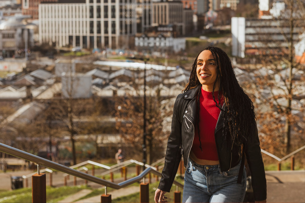 Woman waking up some steps, the Sheffield City Centre is in the background.