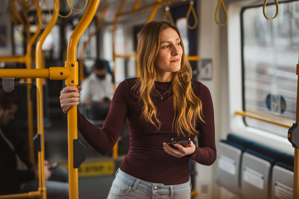 Woman holding the support rails inside of a tram.