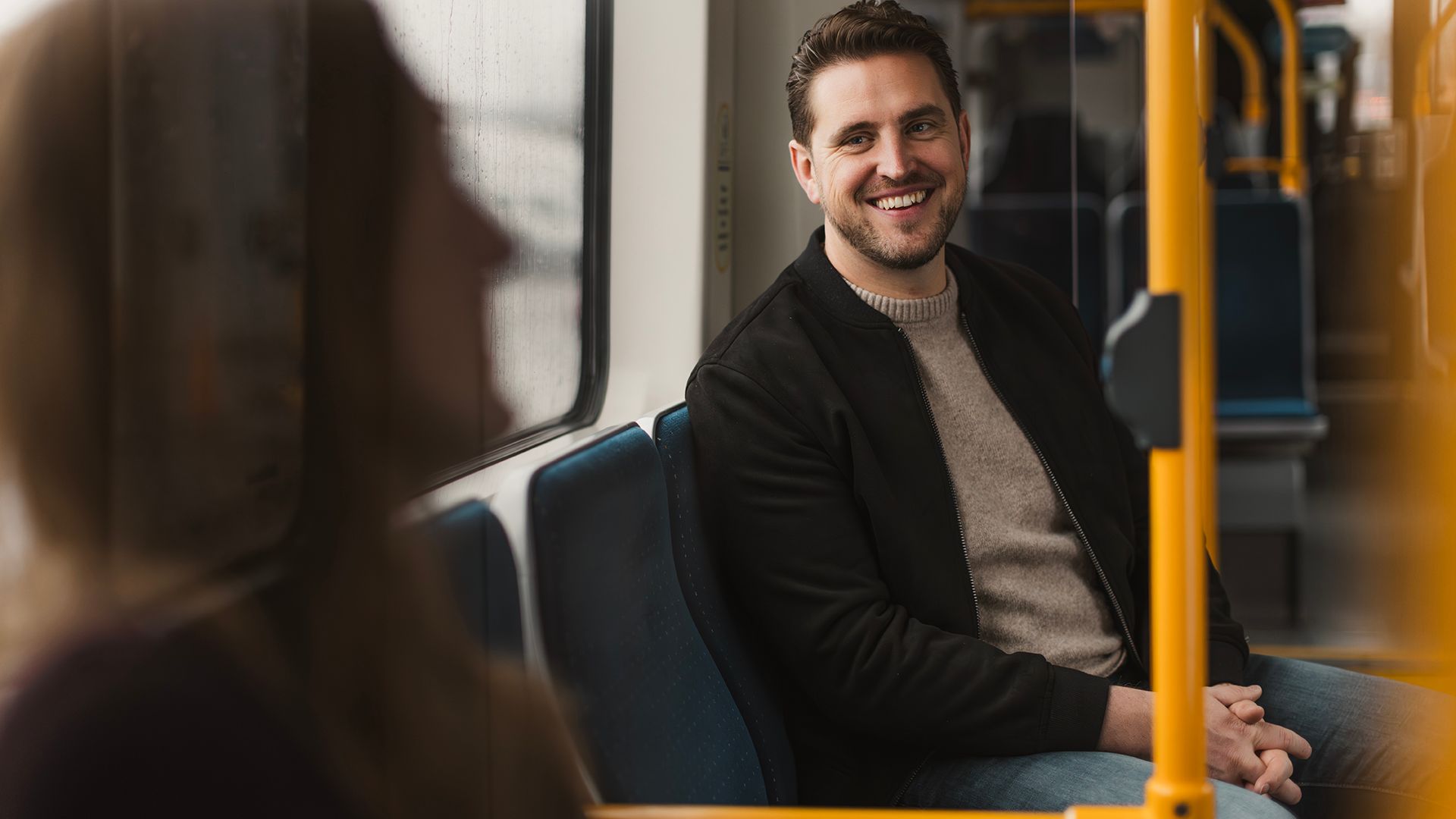 Man on tram smiling at another passenger