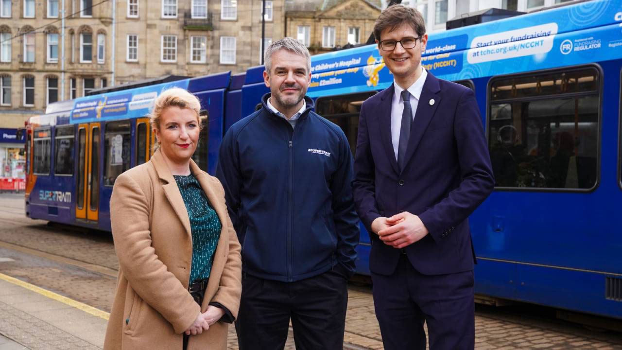 Three people stood infront of a tram